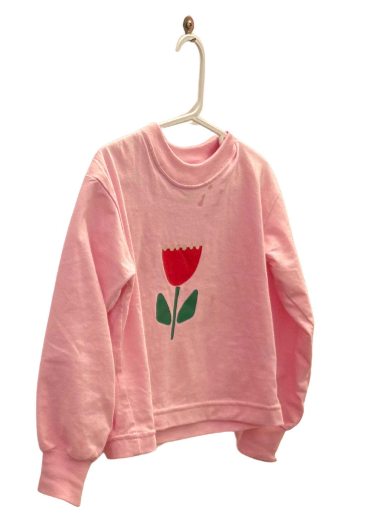 kids long sleeve tshirt featuring a belle sleeve with chunky cuffs detail oversized fit with bold pink green and red flower graphic hand painted logo in white on a baby pink organic cotton tshirt comfortable boxxy fit soft fabric made for playing fun and adventure