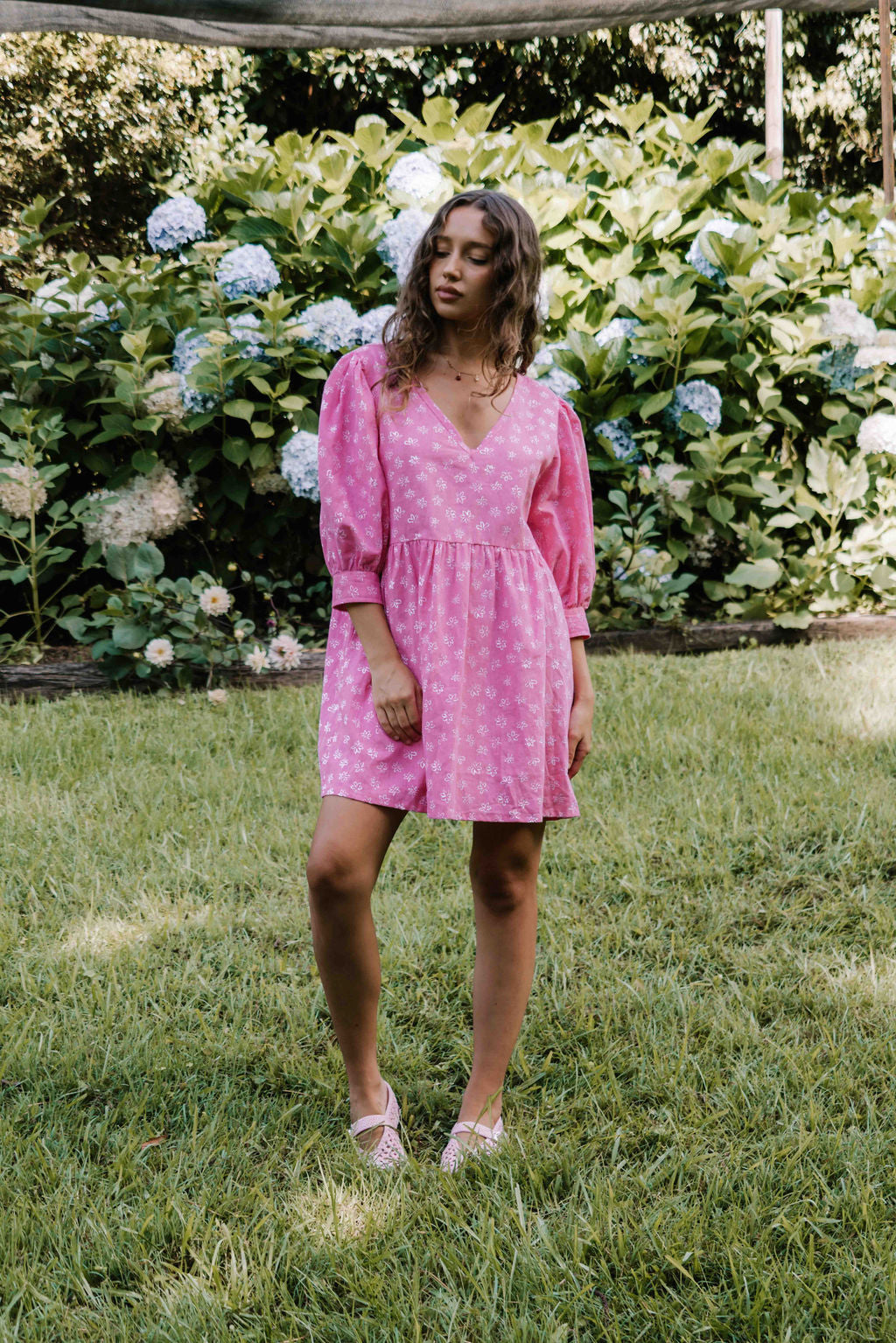 womens v neck mini smock made from 100% highest quality cotton linen. A flattering cut with an adjustable back tie. Puffed 3/4 sleeves and a drop waist with a short dress length. Super comfortable dress, adjustable back tie and in a floral flower print in bright candy pink.