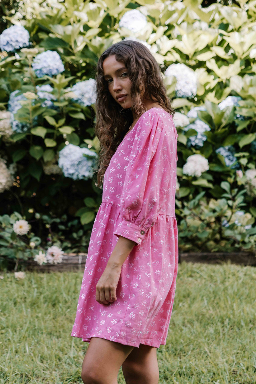 womens v neck mini smock made from 100% highest quality cotton linen. A flattering cut with an adjustable back tie. Puffed 3/4 sleeves and a drop waist with a short dress length. Super comfortable dress, adjustable back tie and in a floral flower print in bright candy pink.