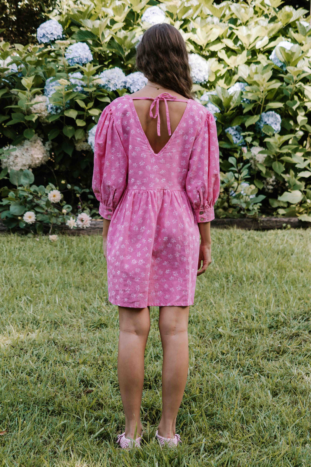 womens v neck mini smock made from 100% highest quality cotton linen. A flattering cut with an adjustable back tie. Puffed 3/4 sleeves and a drop waist with a short dress length. Super comfortable dress, adjustable back tie and in a floral flower print in bright candy pink.