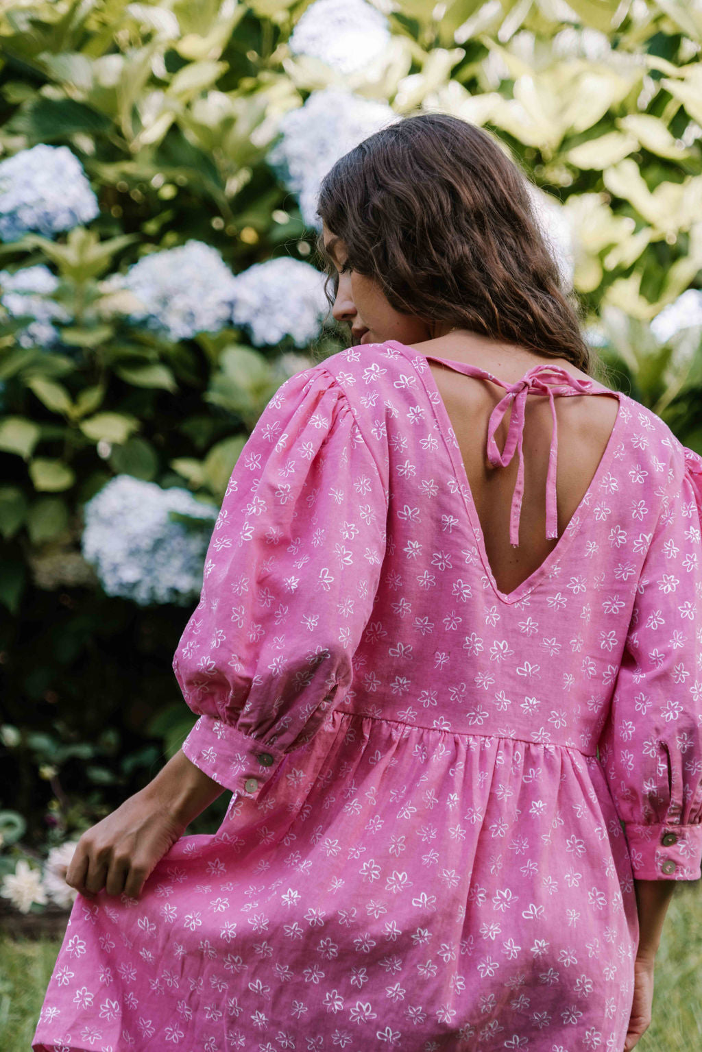 womens v neck mini smock made from 100% highest quality cotton linen. A flattering cut with an adjustable back tie. Puffed 3/4 sleeves and a drop waist with a short dress length. Super comfortable dress, adjustable back tie and in a floral flower print in bright candy pink.