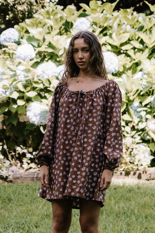 drawstring neckline shift mini dress with a statement balloon long sleeve with elastic wrists, rounded neckline with adjustable bow tie at the front. Hand painted white flower print on a dark mocha brown cotton linen fabric.