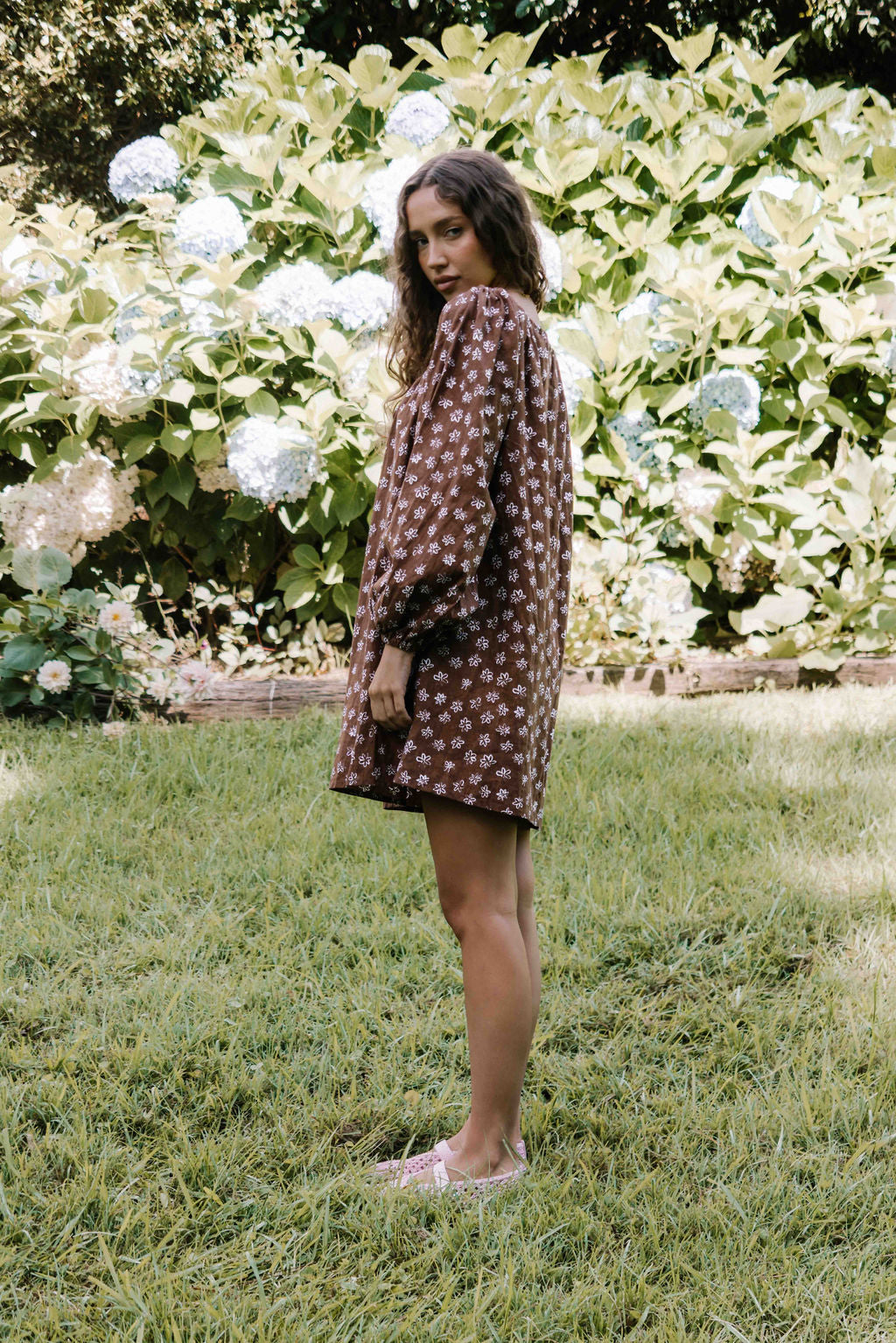 drawstring neckline shift mini dress with a statement balloon long sleeve with elastic wrists, rounded neckline with adjustable bow tie at the front. Hand painted white flower print on a dark mocha brown cotton linen fabric.