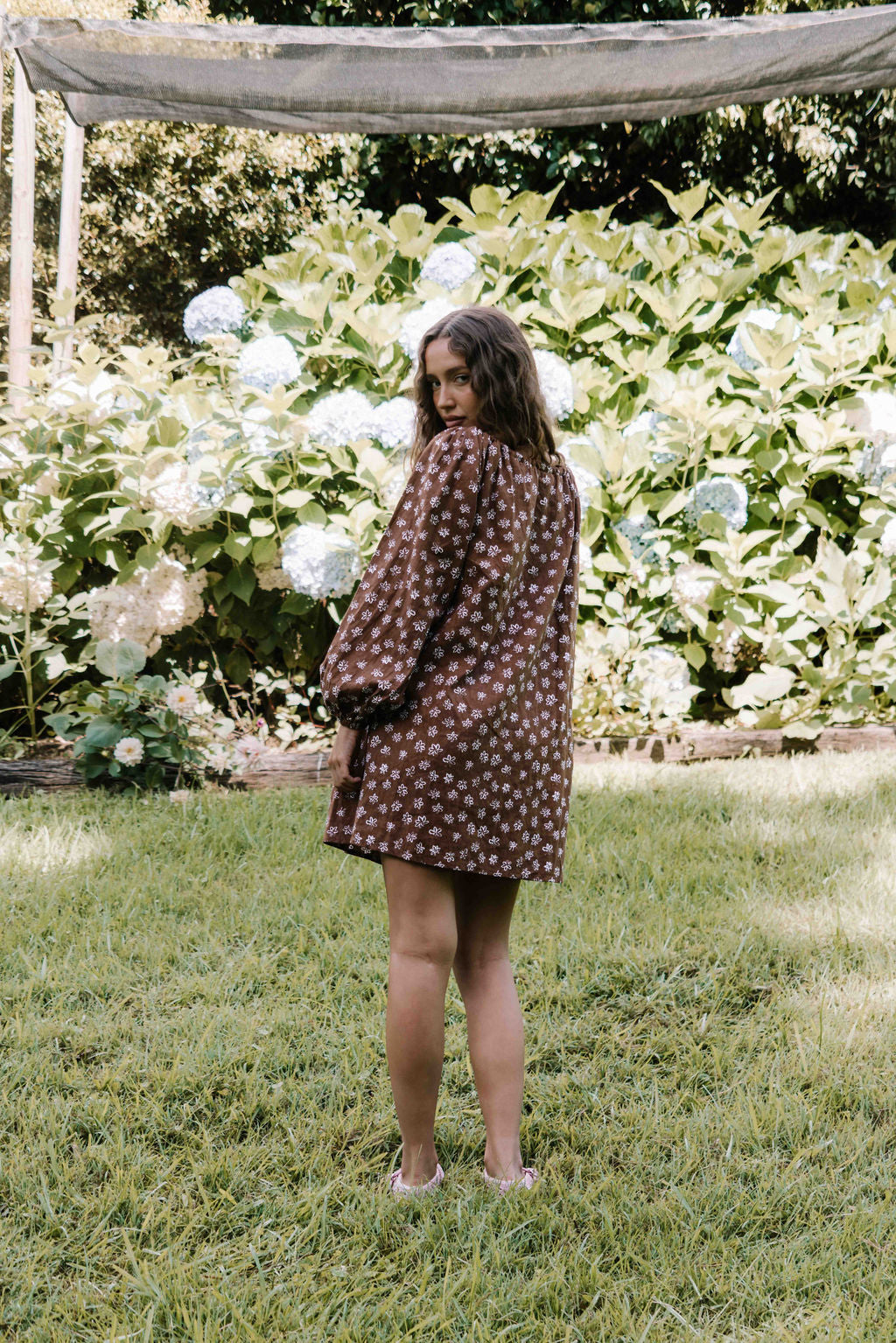drawstring neckline shift mini dress with a statement balloon long sleeve with elastic wrists, rounded neckline with adjustable bow tie at the front. Hand painted white flower print on a dark mocha brown cotton linen fabric.