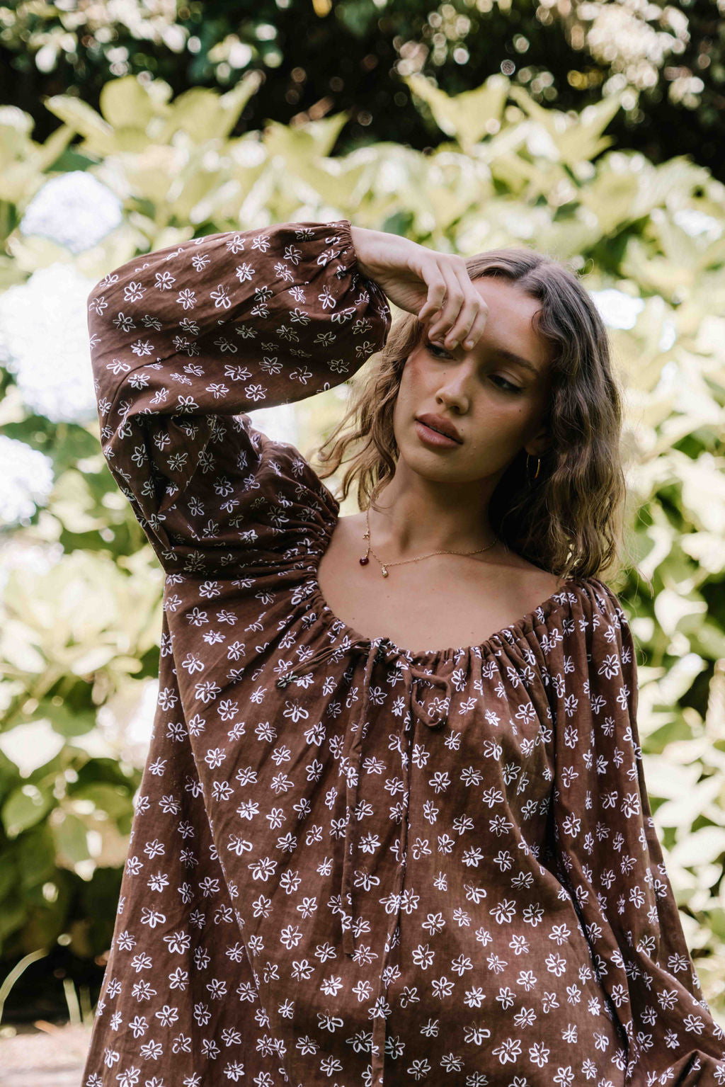 drawstring neckline shift mini dress with a statement balloon long sleeve with elastic wrists, rounded neckline with adjustable bow tie at the front. Hand painted white flower print on a dark mocha brown cotton linen fabric.