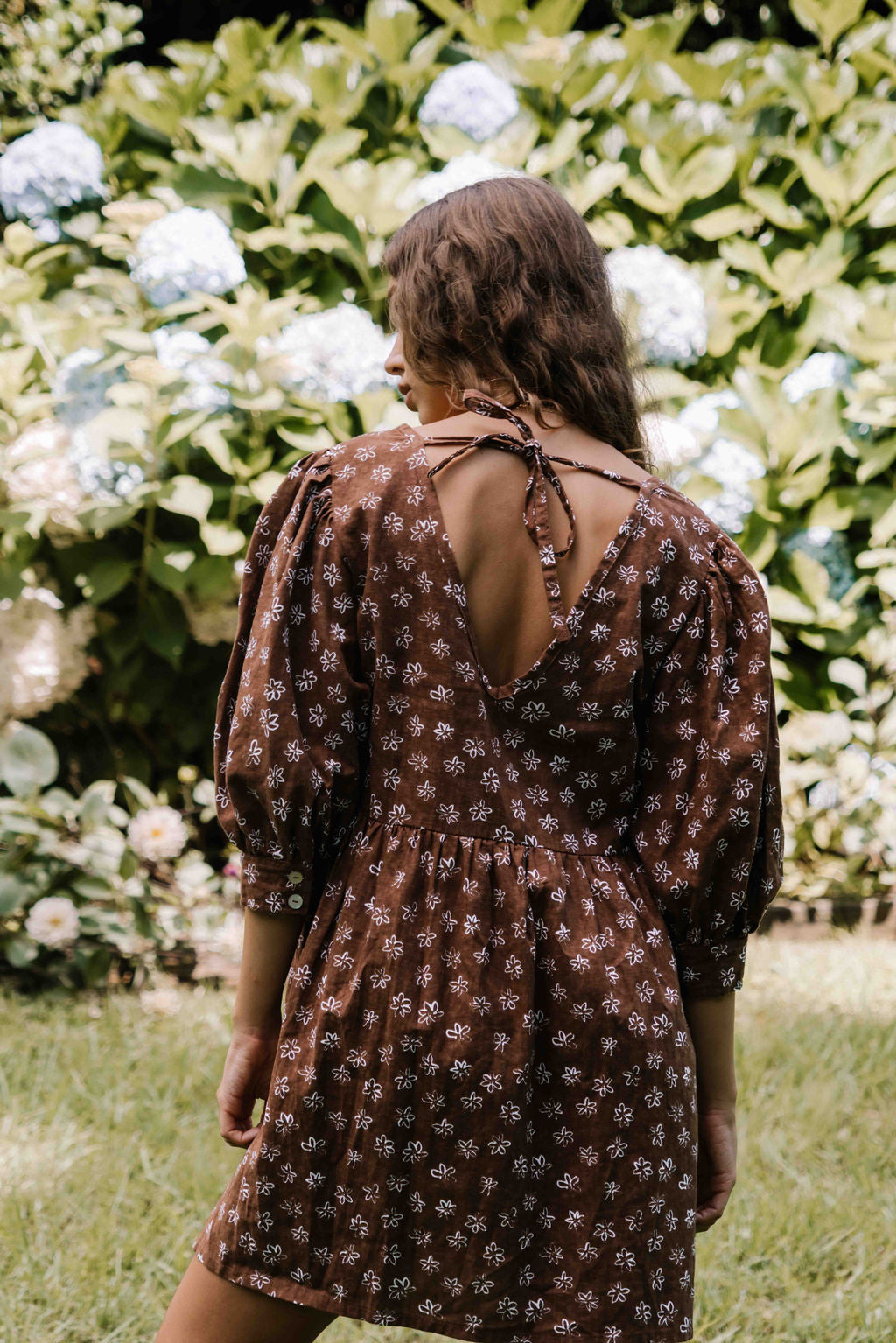 womens v neck mini smock made from 100% highest quality cotton linen. A flattering cut with an adjustable back tie. Puffed 3/4 sleeves and a drop waist with a short dress length. Super comfortable dress, adjustable back tie and in a floral flower print in mocha chocolate brown colour.