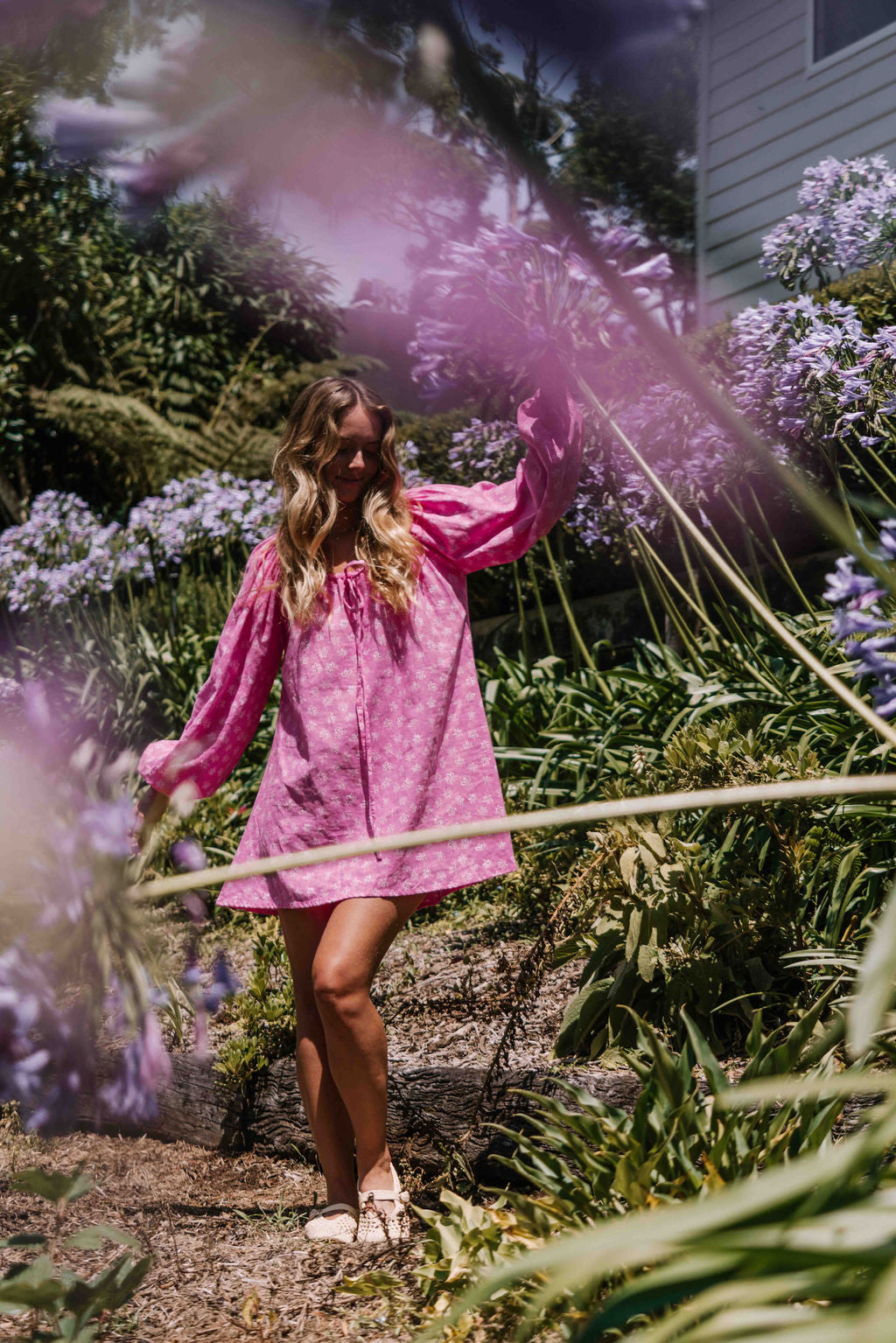 drawstring neckline shift mini dress with a statement balloon long sleeve with elastic wrists, rounded neckline with adjustable bow tie at the front. Hand painted white flower print on a bright candy pink cotton linen fabric.
