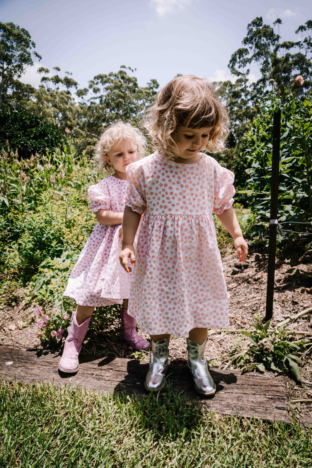 kids smock style dress in orange and white flower floral print with puff sleeves and adjustable back made from a cotton linen blend fabric thats soft