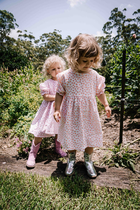 kids smock style dress in orange and white flower floral print with puff sleeves and adjustable back made from a cotton linen blend fabric thats soft