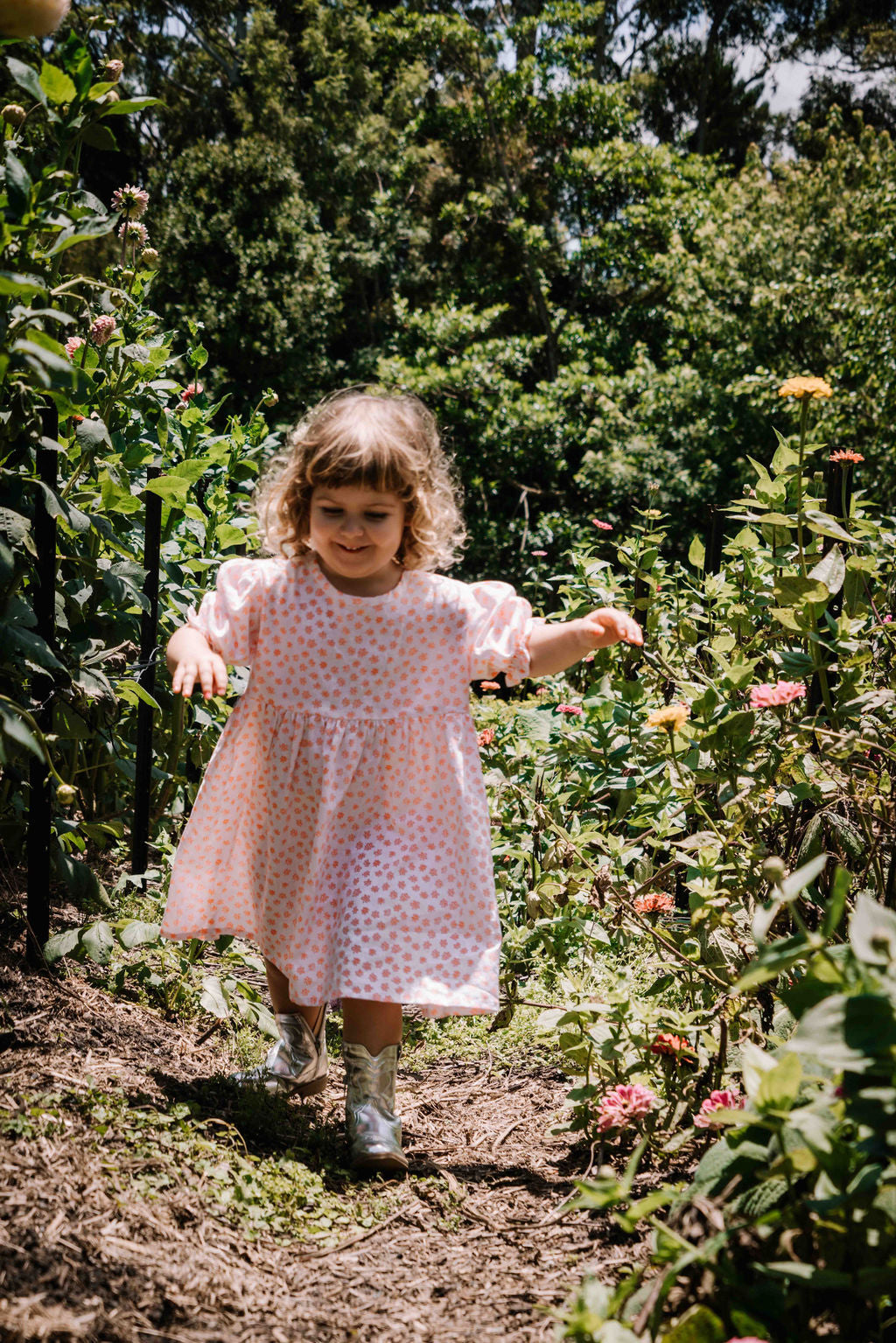 kids smock style dress in orange and white flower floral print with puff sleeves and adjustable back made from a cotton linen blend fabric thats soft