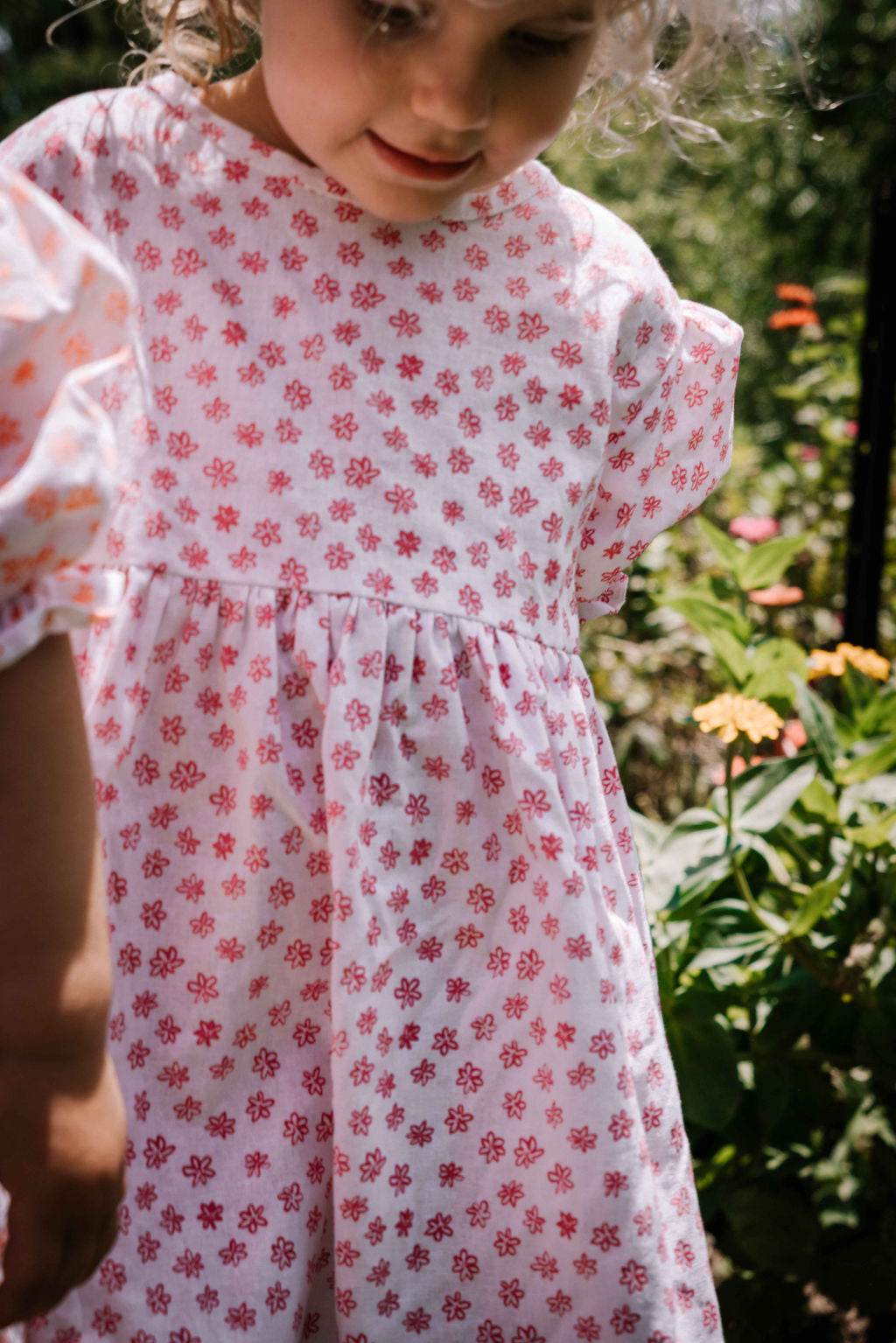 kids smock style dress in pink and white flower floral print with puff sleeves and adjustable back made from a cotton linen blend fabric thats soft