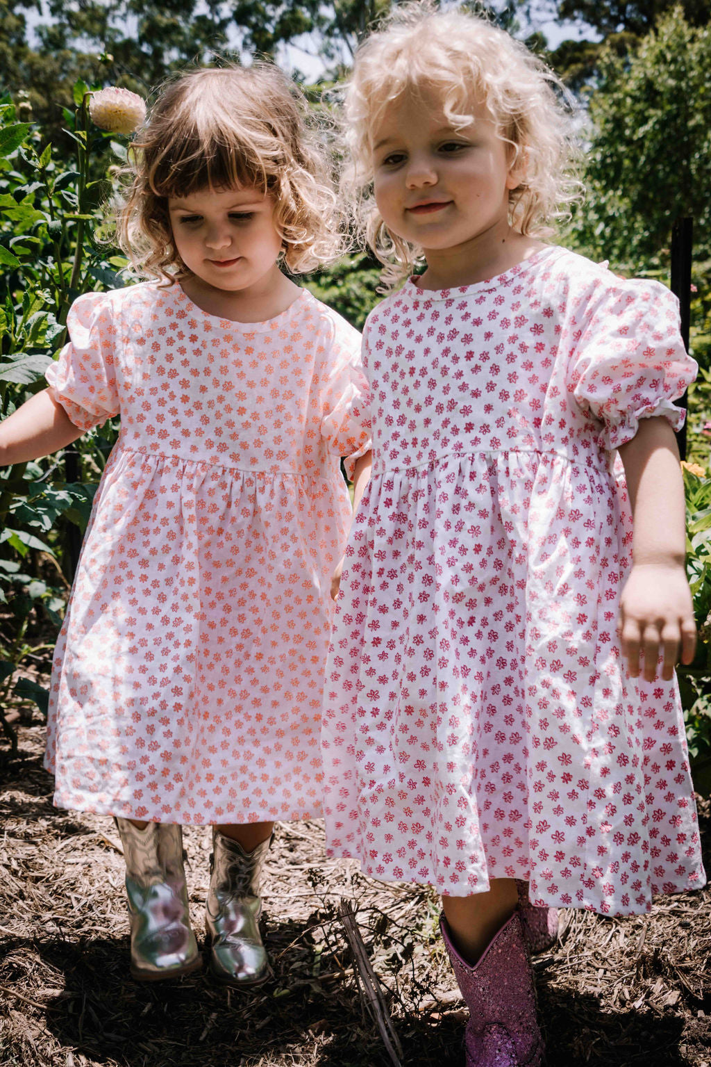 kids smock style dress in pink and white flower floral print with puff sleeves and adjustable back made from a cotton linen blend fabric thats soft