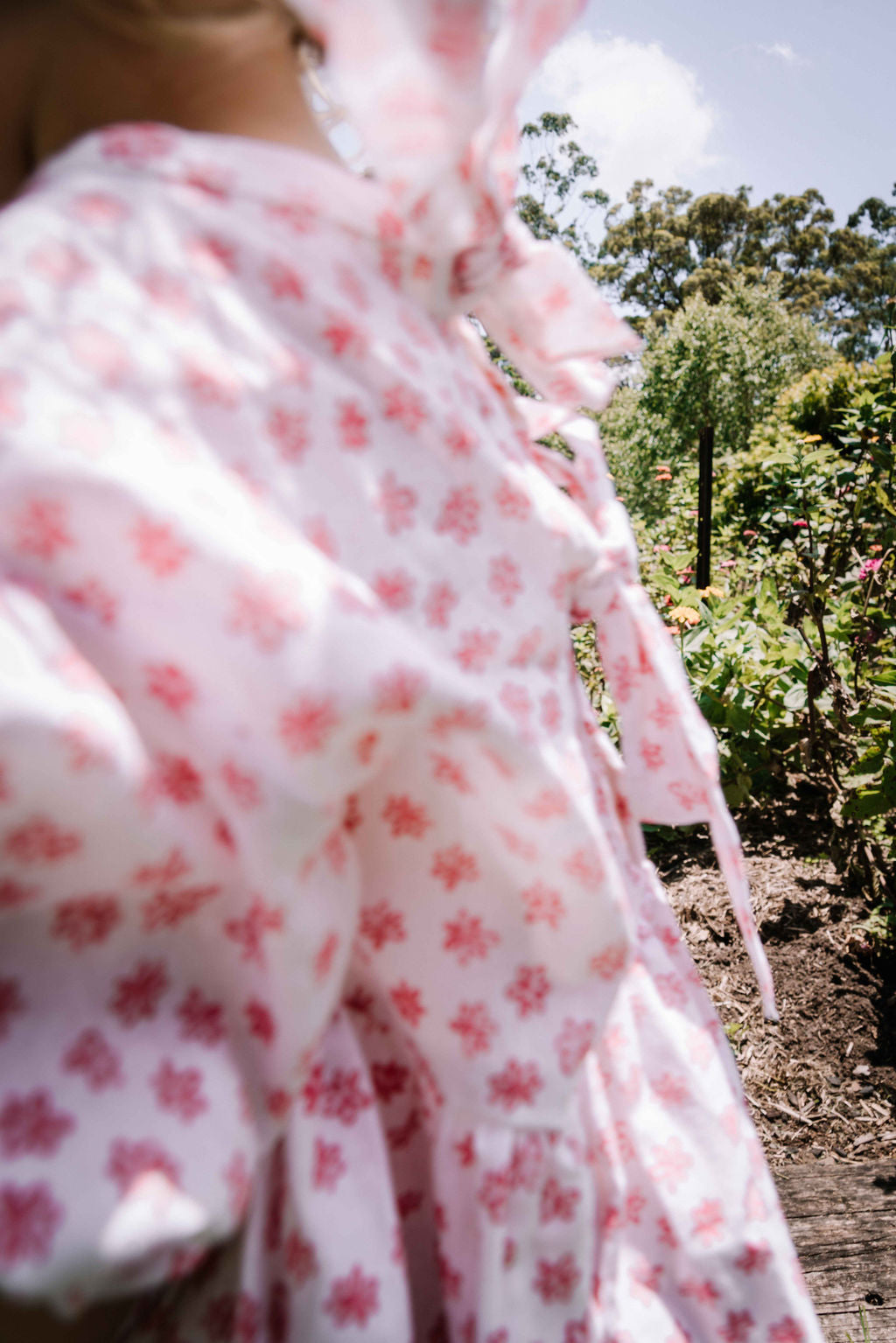 kids smock style dress in pink and white flower floral print with puff sleeves and adjustable back made from a cotton linen blend fabric thats soft