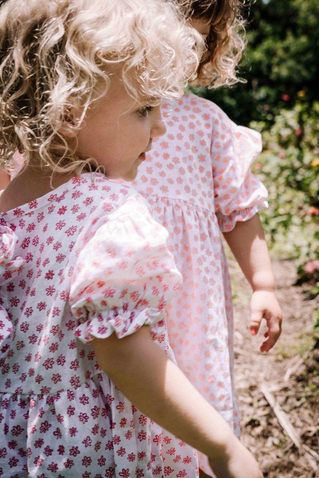 kids smock style dress in pink and white flower floral print with puff sleeves and adjustable back made from a cotton linen blend fabric thats soft