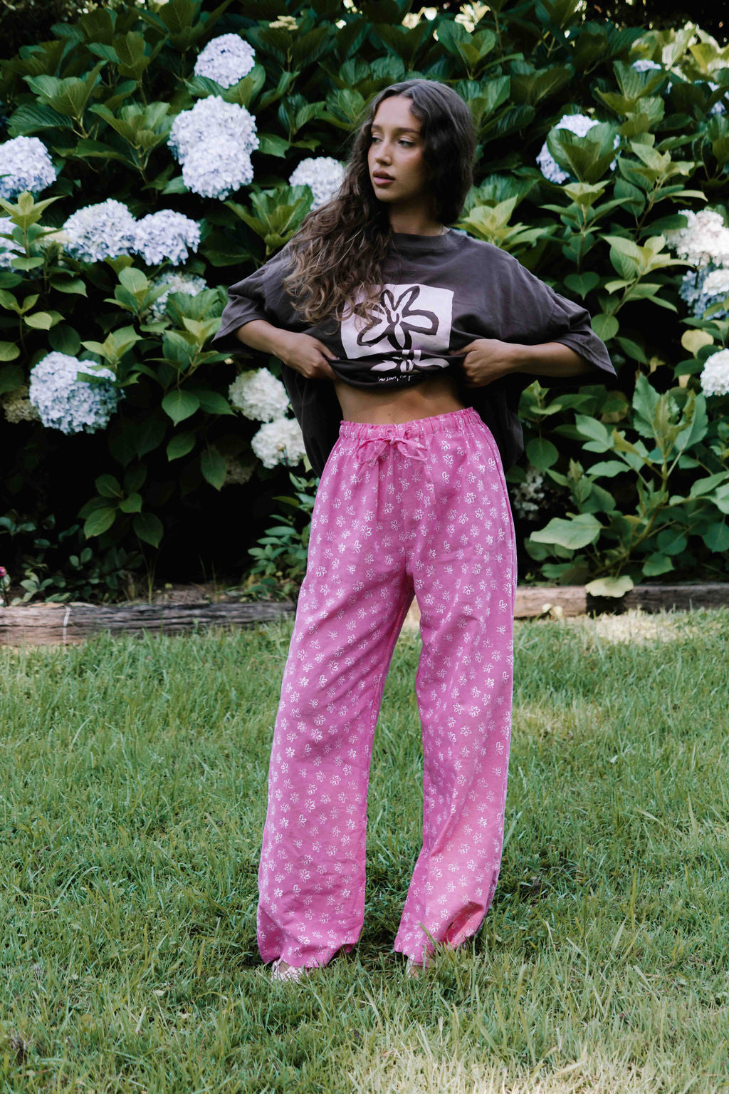 womens wide leg full length relaxed fit pant in abright candy pink cotton linen fabric with a hand painted flower print in white elastic waist with drawstring wide leg fit to the ankles