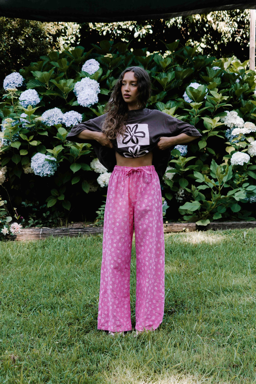 womens wide leg full length relaxed fit pant in abright candy pink cotton linen fabric with a hand painted flower print in white elastic waist with drawstring wide leg fit to the ankles