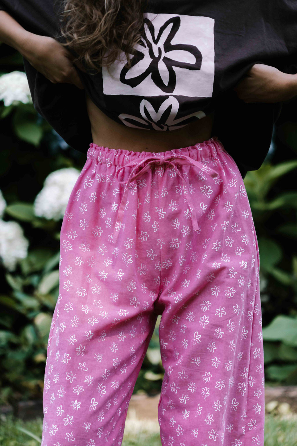 womens wide leg full length relaxed fit pant in abright candy pink cotton linen fabric with a hand painted flower print in white elastic waist with drawstring wide leg fit to the ankles
