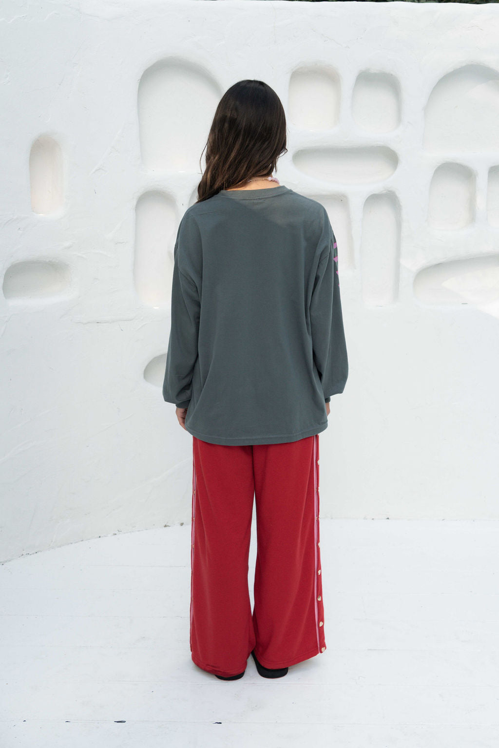 Women’s oversized long-sleeve t-shirt in charcoal, featuring belle sleeves gathered into chunky cuffs. Designed in ultra-soft 100% organic cotton, it showcases a bold flower graphic in pink, red, and green on the front and repeated down each sleeve, with a small 'häll' logo detail.