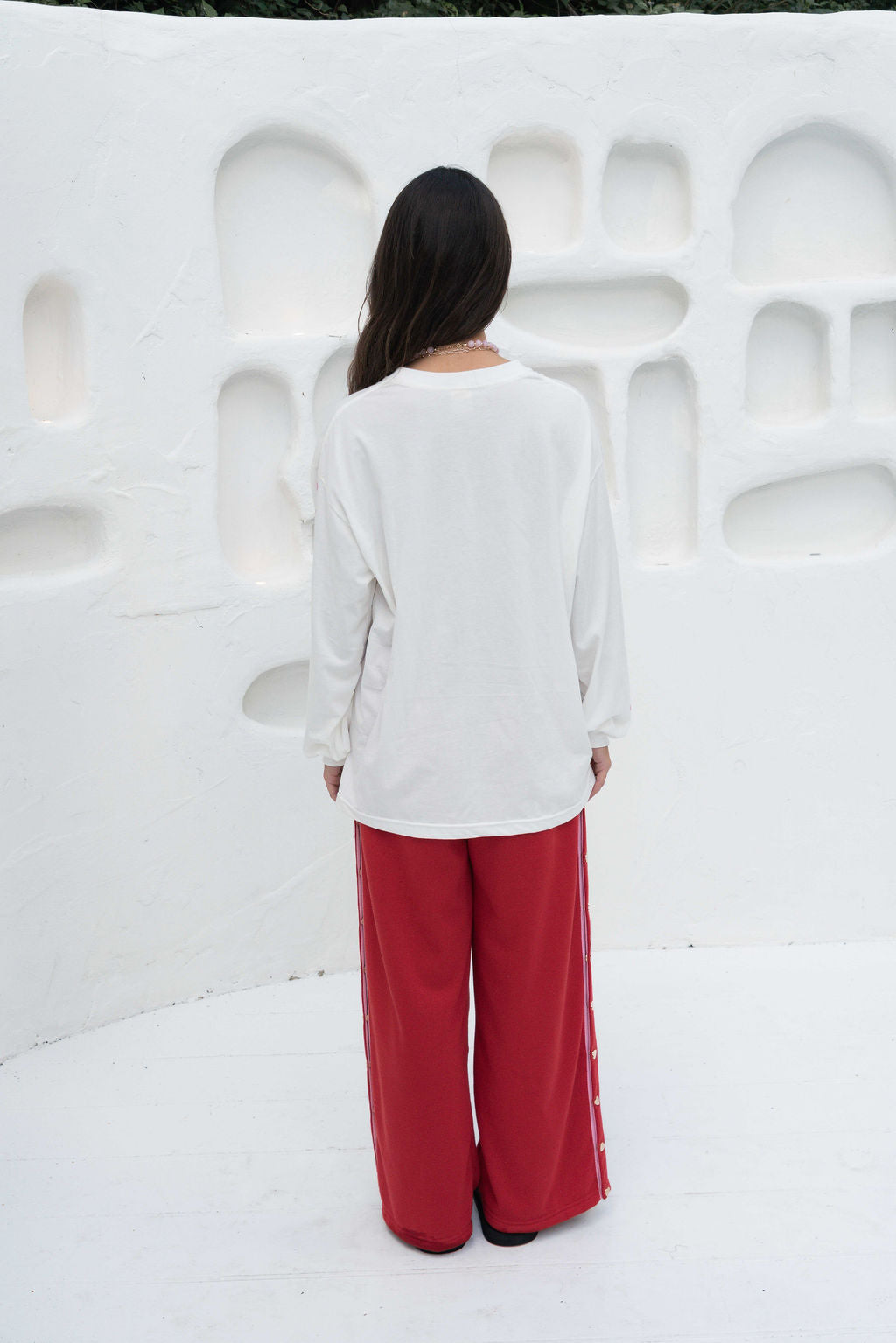 Women’s oversized long-sleeve t-shirt in white, featuring belle sleeves gathered into chunky cuffs. Designed in ultra-soft 100% organic cotton, it showcases a bold flower graphic in pink and green on the front and repeated down each sleeve, with a small 'häll' logo detail.