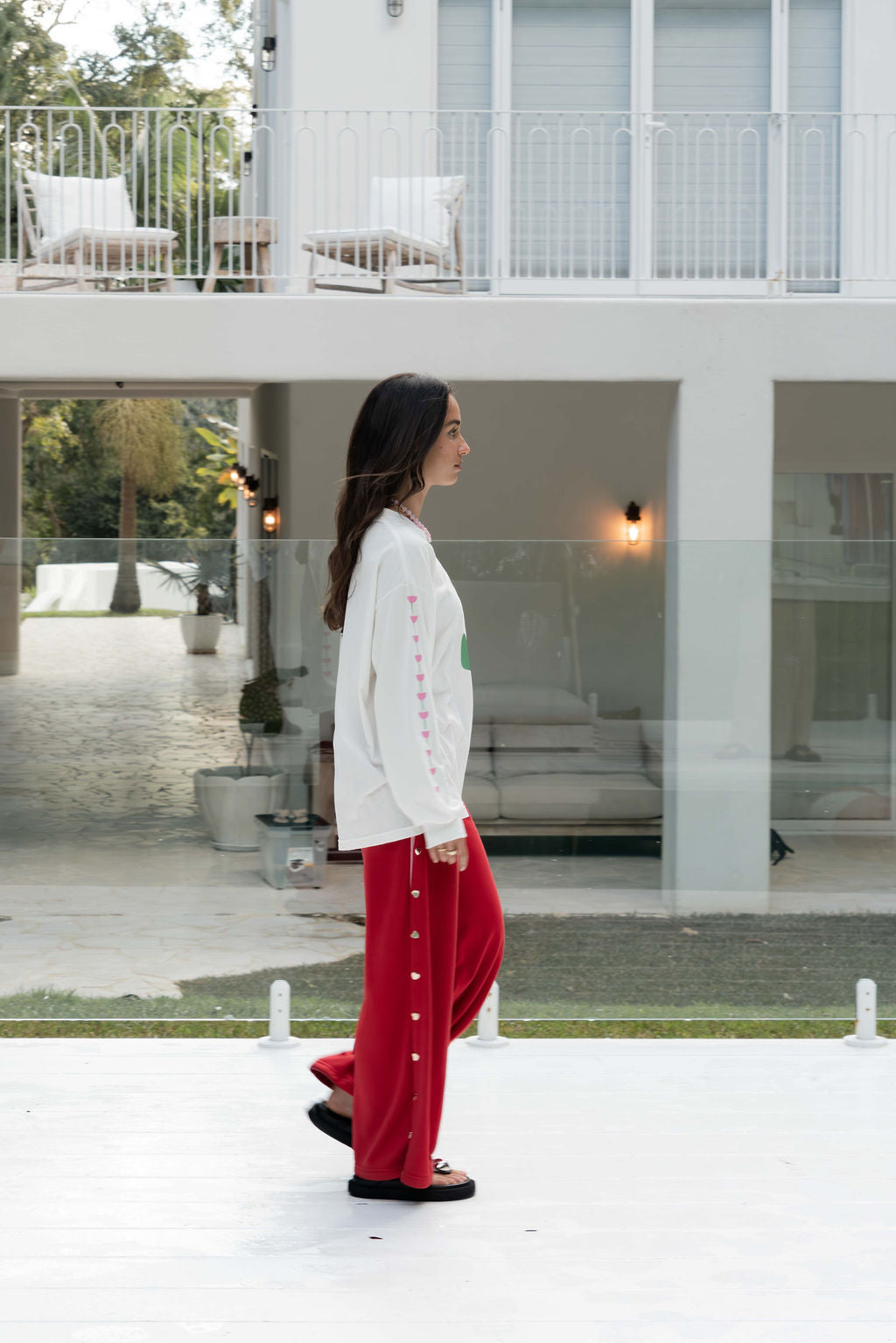 Women’s oversized long-sleeve t-shirt in white, featuring belle sleeves gathered into chunky cuffs. Designed in ultra-soft 100% organic cotton, it showcases a bold flower graphic in pink and green on the front and repeated down each sleeve, with a small 'häll' logo detail.