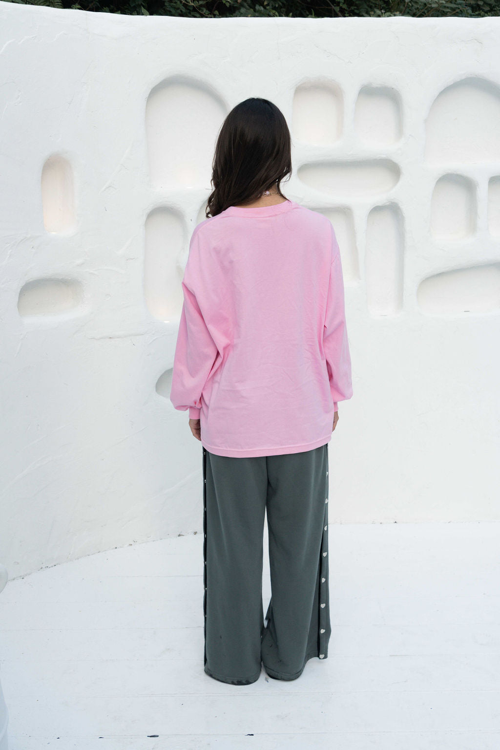 Women’s oversized long-sleeve t-shirt in baby pink, featuring belle sleeves gathered into chunky cuffs. Designed in ultra-soft 100% organic cotton, it showcases a bold flower graphic in pink, red, and green on the front and repeated down each sleeve, with a small 'häll' logo detail.