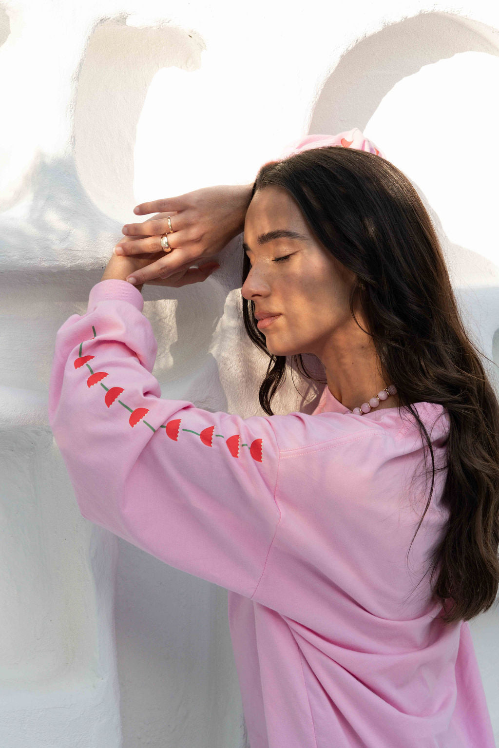 Women’s oversized long-sleeve t-shirt in baby pink, featuring belle sleeves gathered into chunky cuffs. Designed in ultra-soft 100% organic cotton, it showcases a bold flower graphic in pink, red, and green on the front and repeated down each sleeve, with a small 'häll' logo detail.