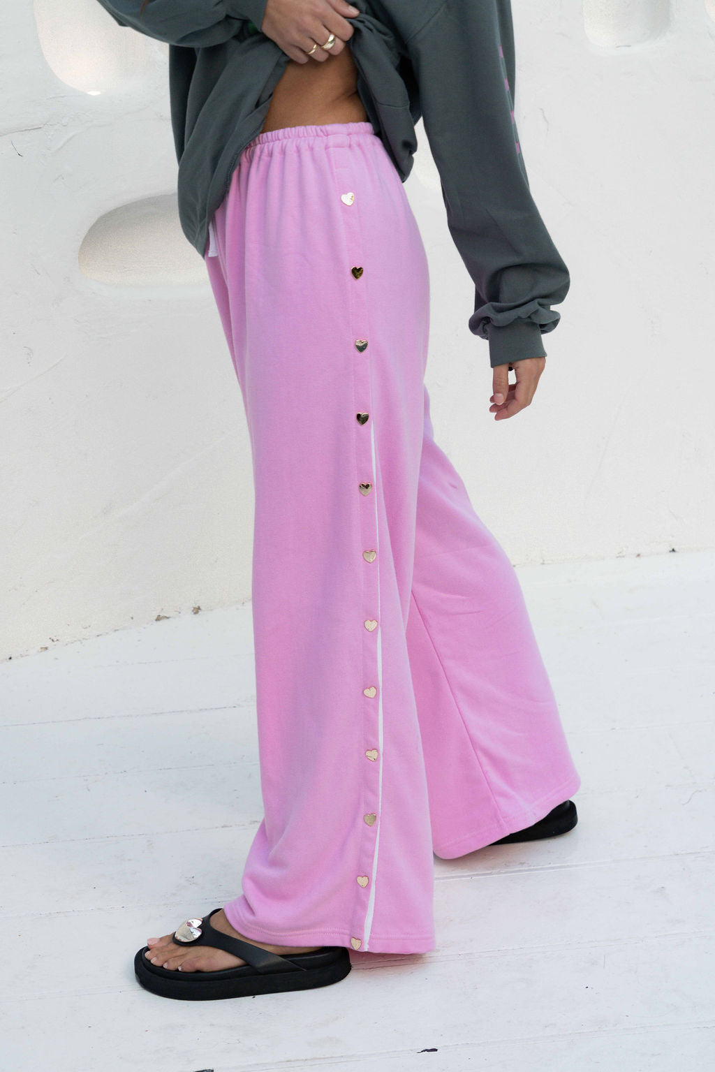 womens wide leg full length relaxed fit pant in a pink terry cotton fabric with a white drawstring and gold heart shape push studs down each leg wide leg fit to the ankle