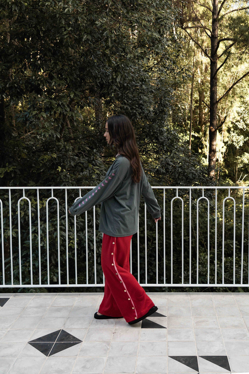 Women’s oversized long-sleeve t-shirt in charcoal, featuring belle sleeves gathered into chunky cuffs. Designed in ultra-soft 100% organic cotton, it showcases a bold flower graphic in pink, red, and green on the front and repeated down each sleeve, with a small 'häll' logo detail.
