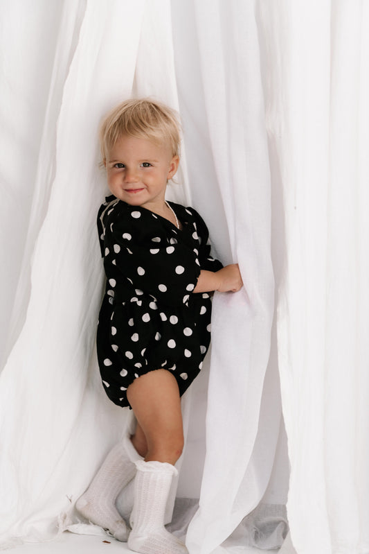 baby toddler romper in the cutest polkadot print in black and white colour with white dots a v neck front a adjustable back with ties long sleeves with elastic cuffs