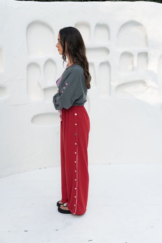 womens wide leg full length relaxed fit pant in a red terry cotton fabric with a pink drawstring and gold heart shape push studs down each leg wide leg fit to the ankle