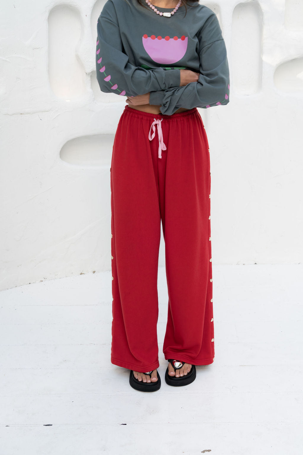 womens wide leg full length relaxed fit pant in a red terry cotton fabric with a pink drawstring and gold heart shape push studs down each leg wide leg fit to the ankle