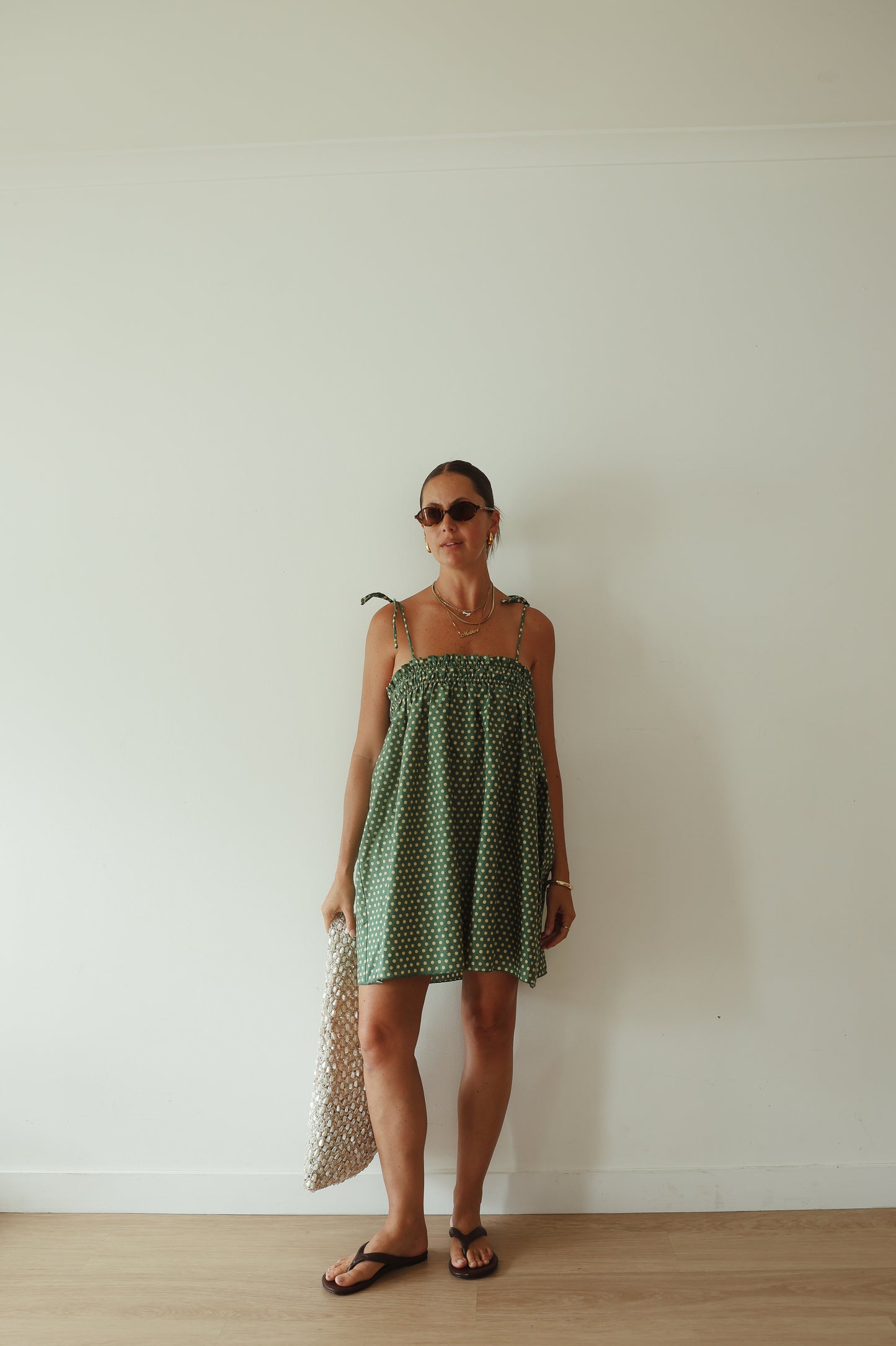 A stunning green mini smock dress with a ruched bust and adjustable spagetti shoulder straps that tie. The fabric is a light weight 100% soft cotton in vibrant green with white yellow polkadots.