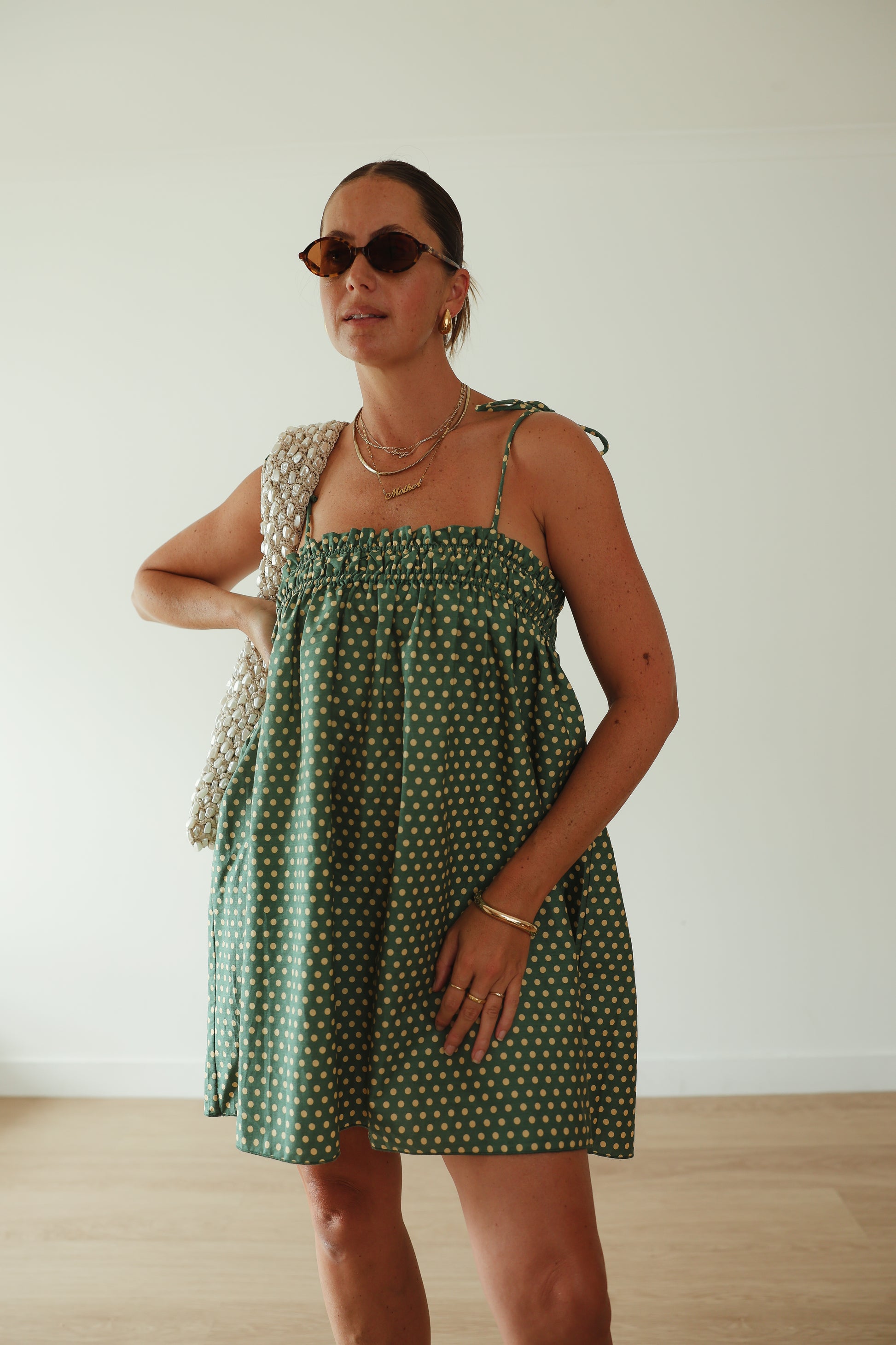 A stunning green mini smock dress with a ruched bust and adjustable spagetti shoulder straps that tie. The fabric is a light weight 100% soft cotton in vibrant green with white yellow polkadots.