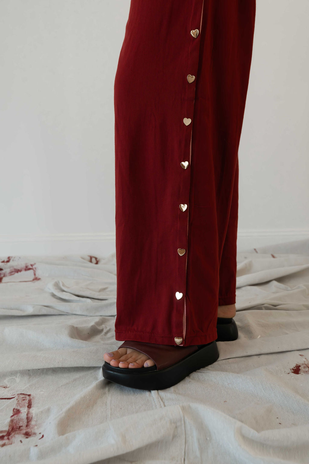 Model wears a two piece set in a deep merlot organic cotton relaxed wide leg pant with side gold heart snap buttons down the leg with an oversized tshirt also in the deep merlot red organic cotton