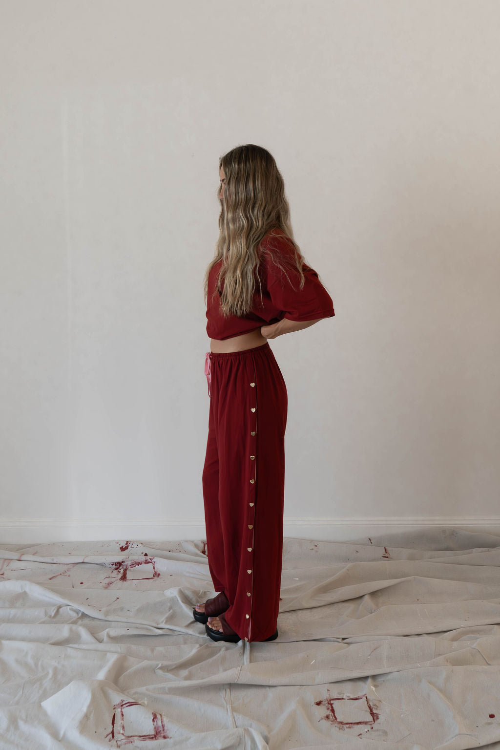 Model wears a two piece set in a deep merlot organic cotton relaxed wide leg pant with side gold heart snap buttons down the leg with an oversized tshirt also in the deep merlot red organic cotton