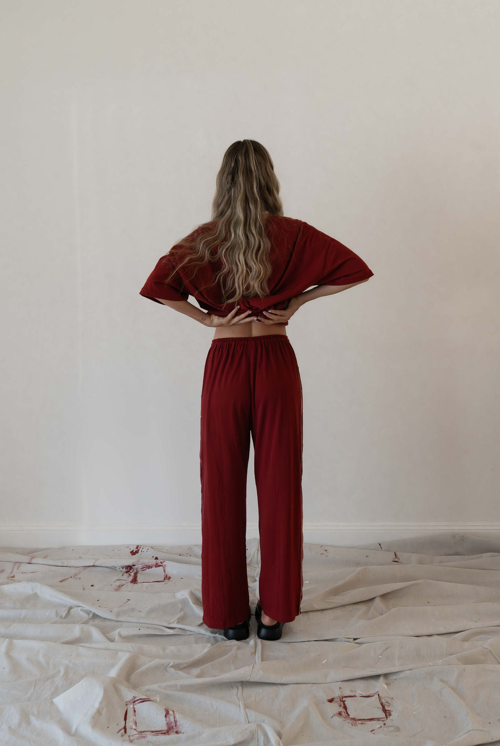 Model wears a two piece set in a deep merlot organic cotton relaxed wide leg pant with side gold heart snap buttons down the leg with an oversized tshirt also in the deep merlot red organic cotton