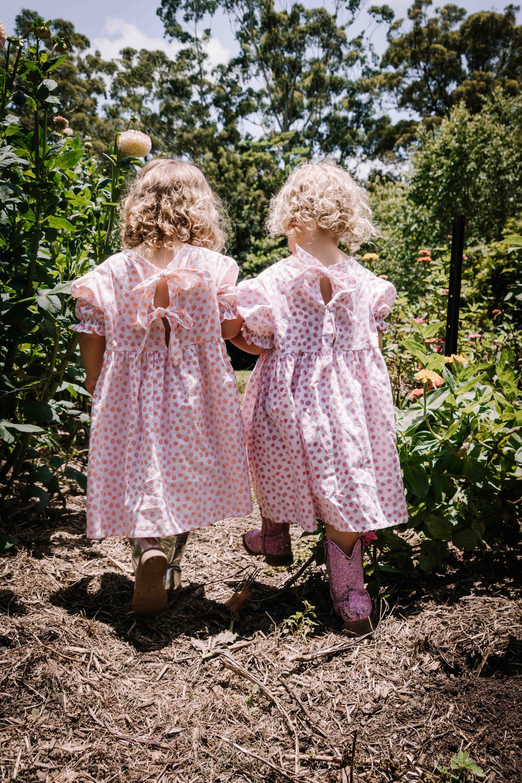  kids smock style dress in orange and white flower floral print with puff sleeves and adjustable back made from a cotton linen blend fabric thats soft 