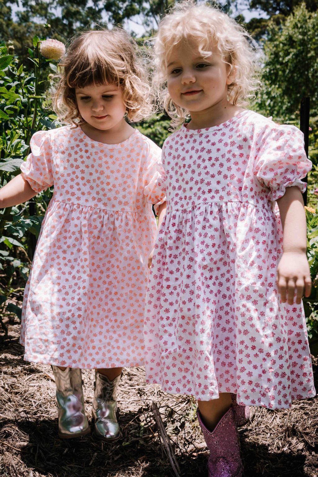 kids smock style dress in pink and white flower floral print with puff sleeves and adjustable back made from a cotton linen blend fabric thats soft 