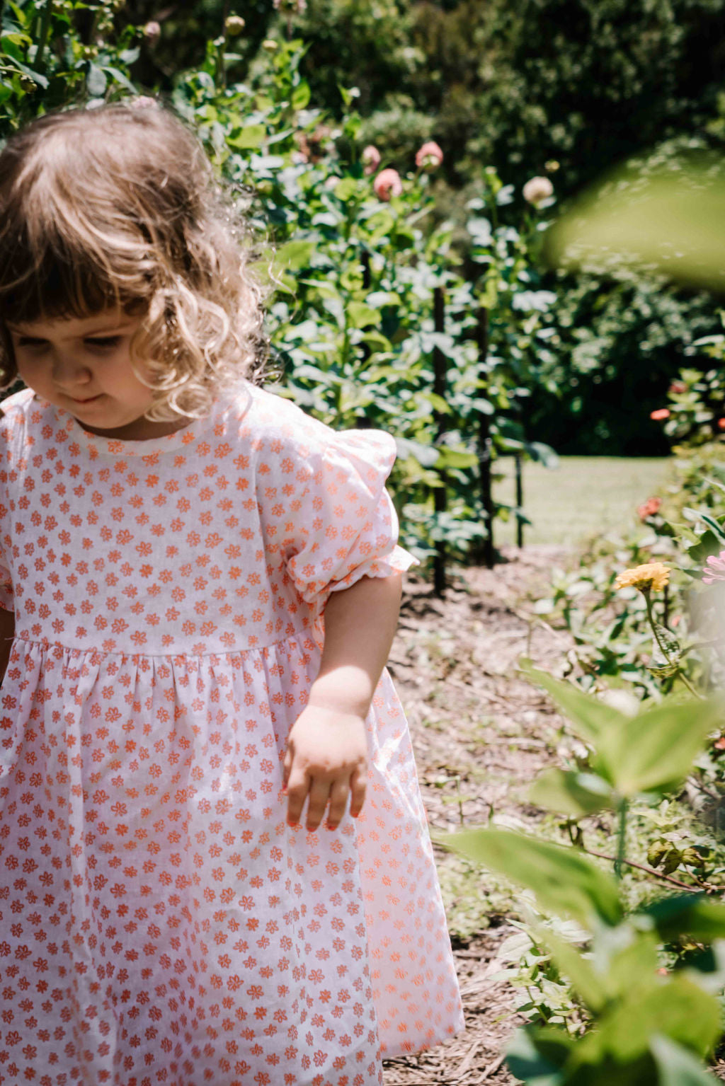  kids smock style dress in orange and white flower floral print with puff sleeves and adjustable back made from a cotton linen blend fabric thats soft 