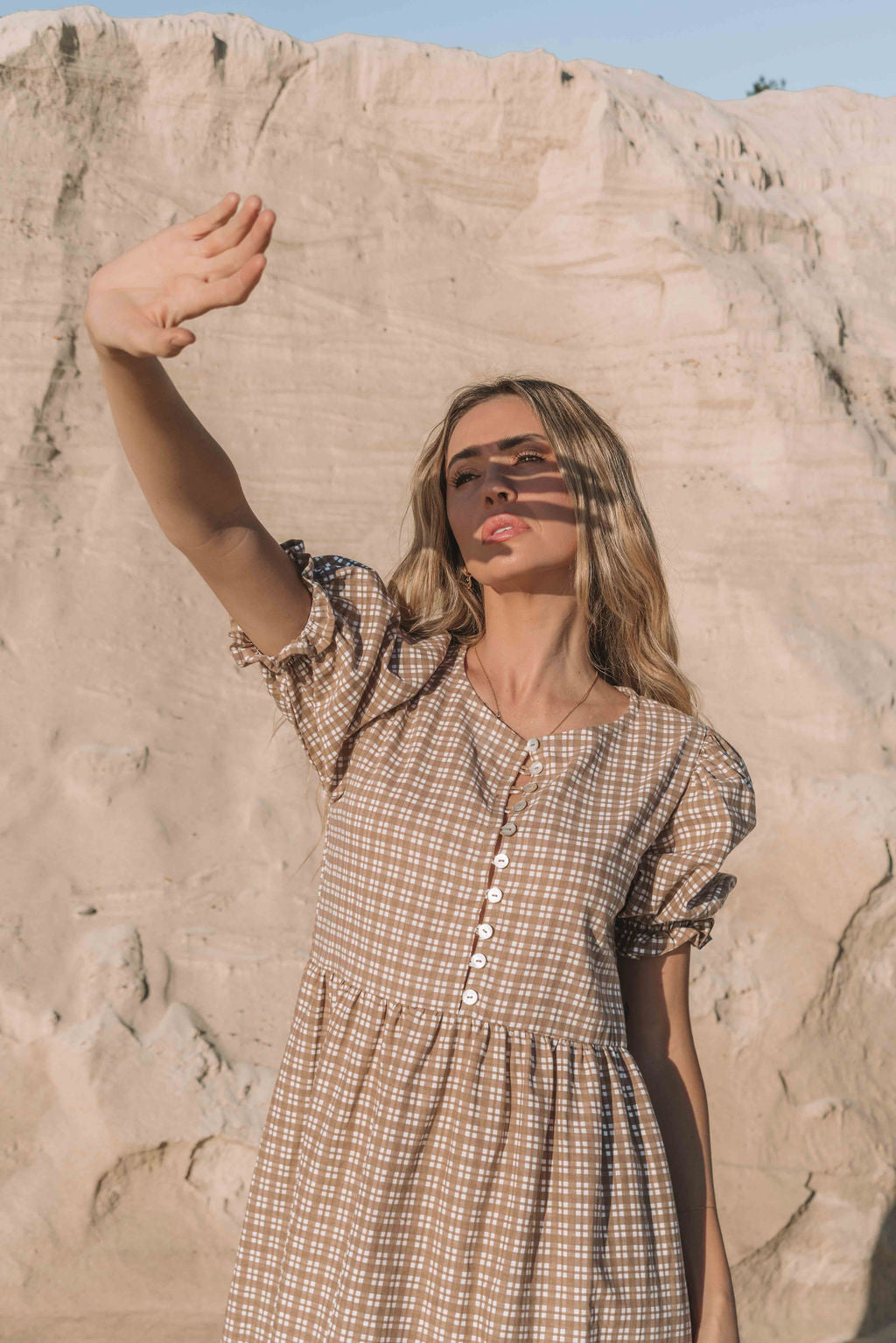 a brown gingham maxi dress with a statement puffed short sleeve with a frill detail, a rounded neckline with a button down front. Breastfeeding friendly style.