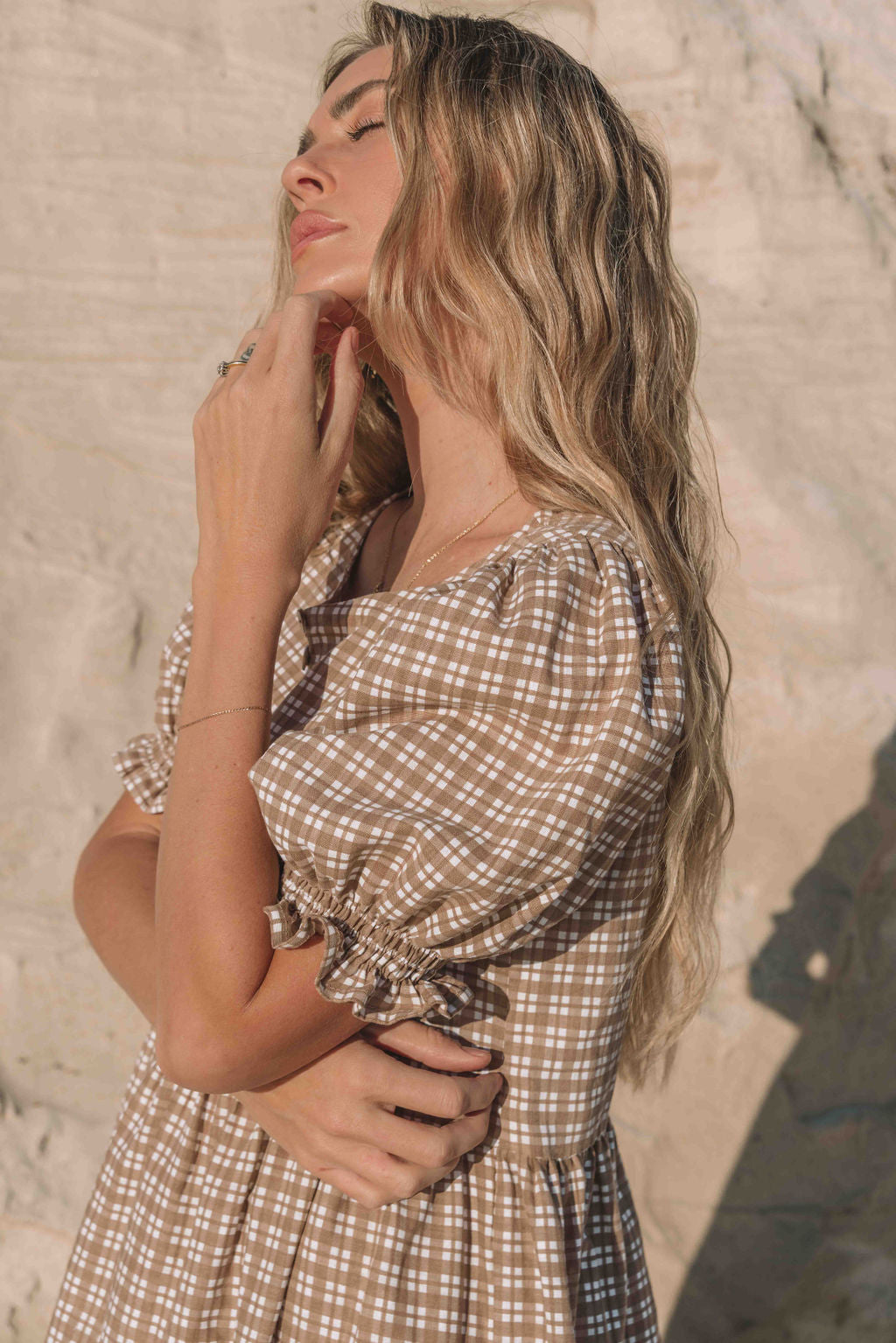 a brown gingham maxi dress with a statement puffed short sleeve with a frill detail, a rounded neckline with a button down front. Breastfeeding friendly style.