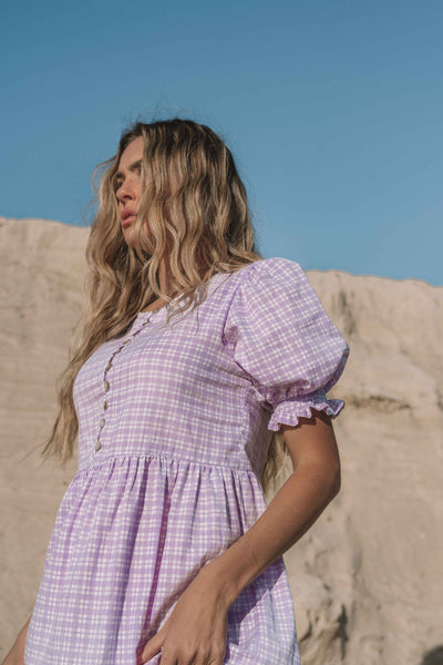 a lilac purple gingham maxi dress with a statement puffed short sleeve with a frill detail, a rounded neckline with a button down front. Breastfeeding friendly style.