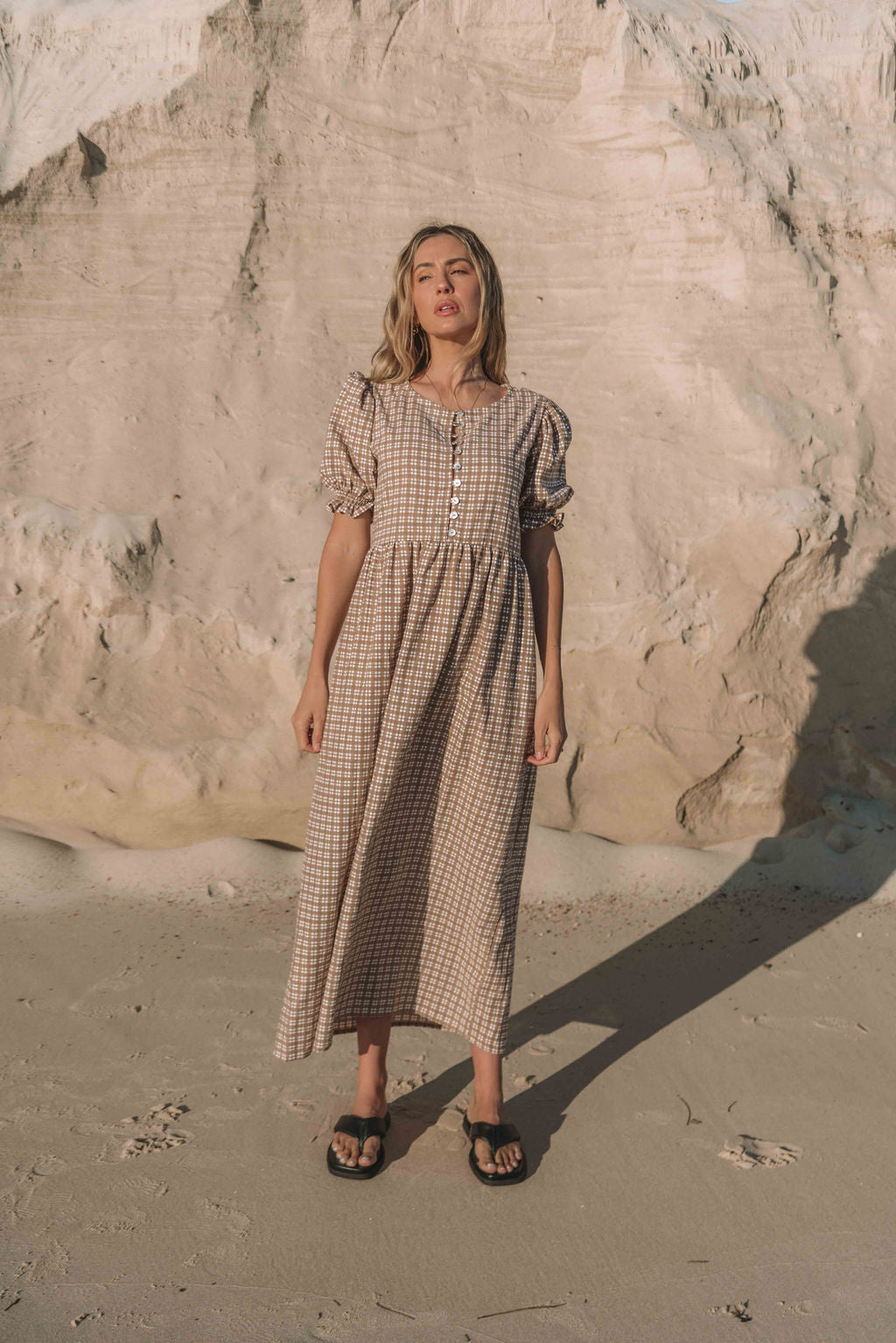 a brown gingham maxi dress with a statement puffed short sleeve with a frill detail, a rounded neckline with a button down front. Breastfeeding friendly style.