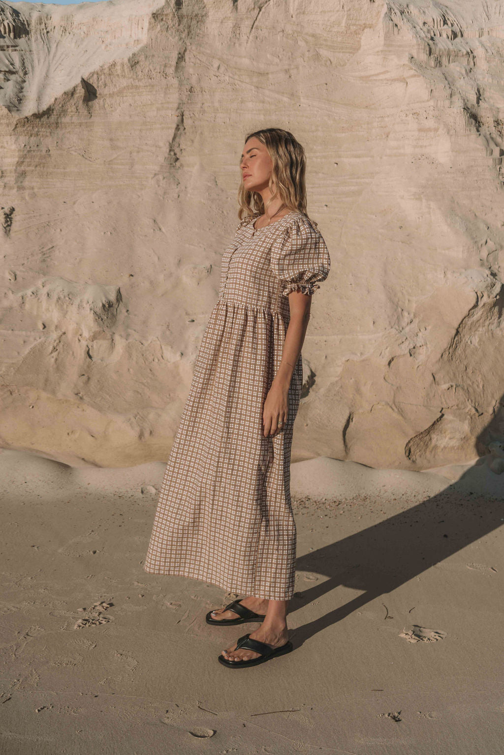 a brown gingham maxi dress with a statement puffed short sleeve with a frill detail, a rounded neckline with a button down front. Breastfeeding friendly style.