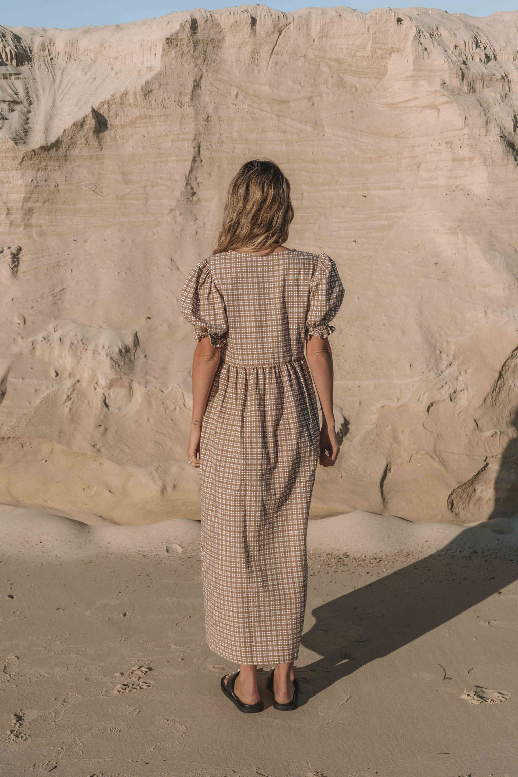 a brown gingham maxi dress with a statement puffed short sleeve with a frill detail, a rounded neckline with a button down front. Breastfeeding friendly style.