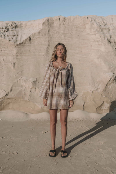 a brown gingham mini dress with a statement balloon long sleeve, rounded neckline with adjustable bow tie at the front