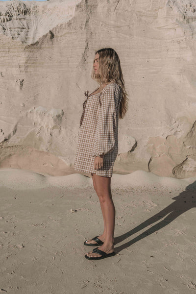 a brown gingham mini dress with a statement balloon long sleeve, rounded neckline with adjustable bow tie at the front