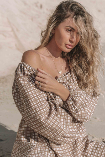 a brown gingham mini dress with a statement balloon long sleeve, rounded neckline with adjustable bow tie at the front