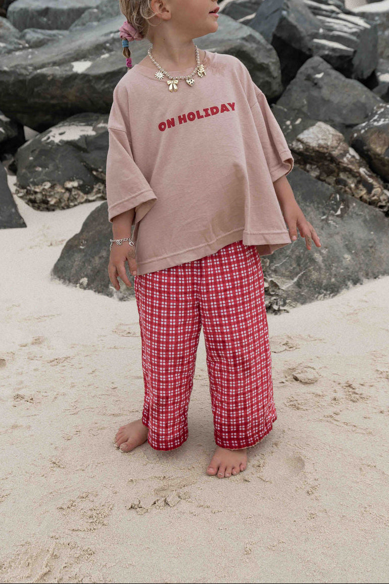 Children's t-shirt made from soft 100% orgaic cotton in a dusty pink oversized fit with red ‘ON HOLIDAY’ graphic. The shirt has a relaxed, comfy fit.

