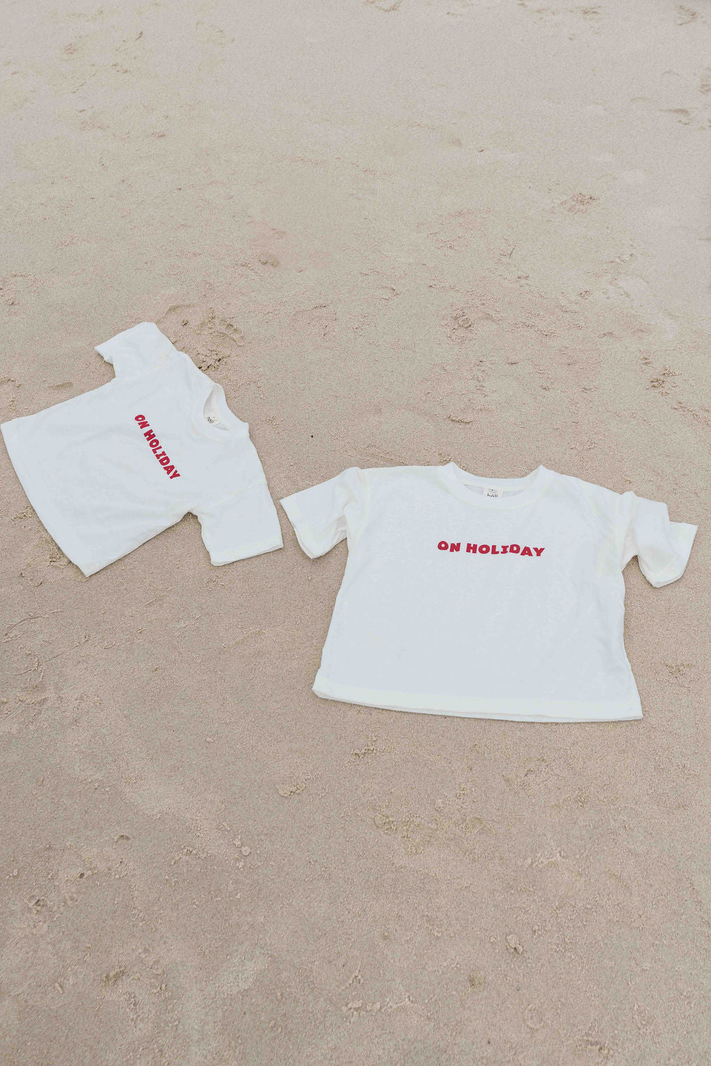Children's t-shirt made from soft 100% orgaic cotton in a off white oversized fit with red ‘ON HOLIDAY’ graphic. The shirt has a relaxed, comfy fit.